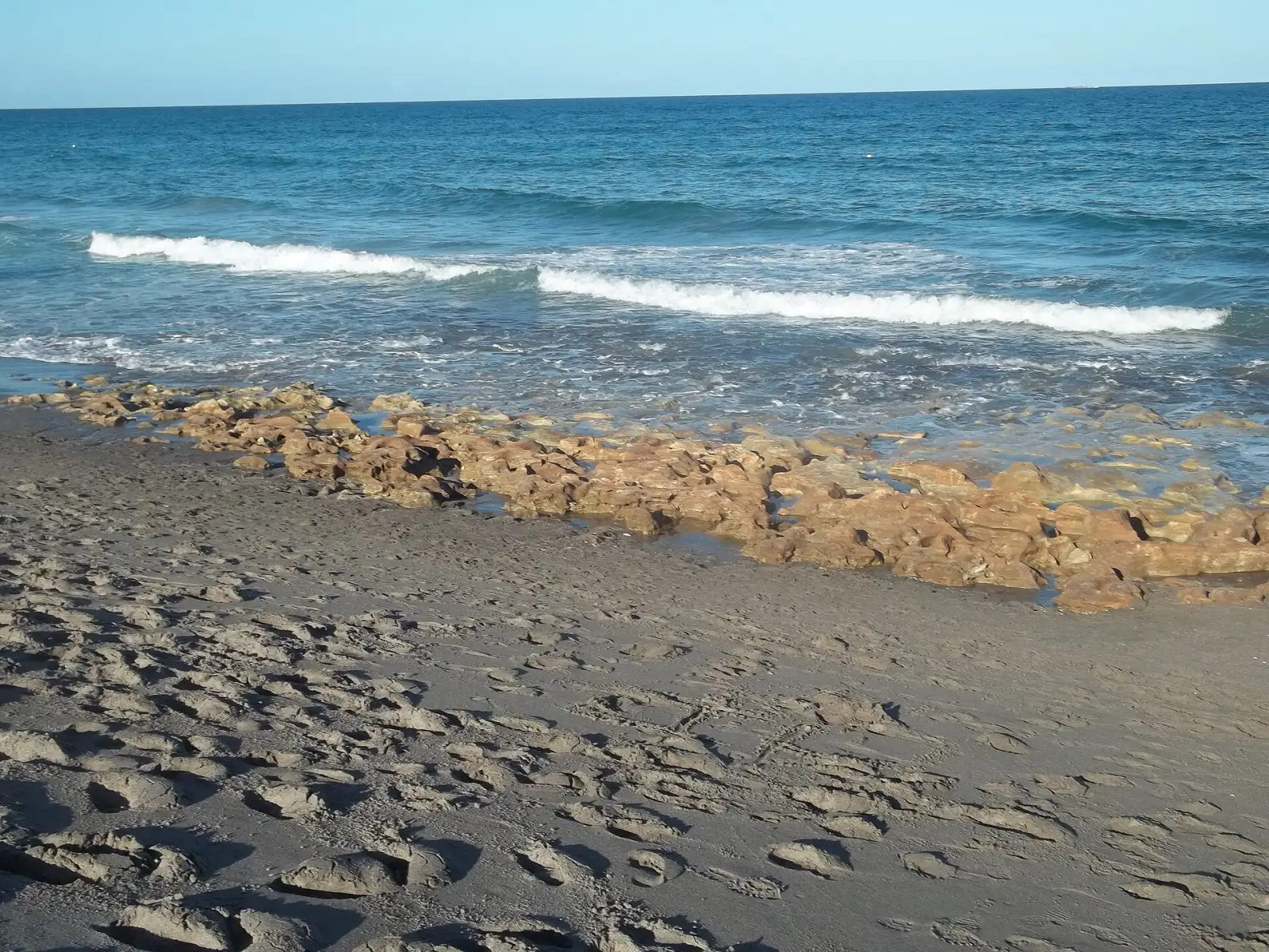 Waves break over rocks on the beach at Coral Cove Park, north of the Jupiter Inlet.